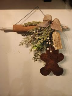 a christmas decoration hanging on the wall next to a wooden stick with a bow and ornament