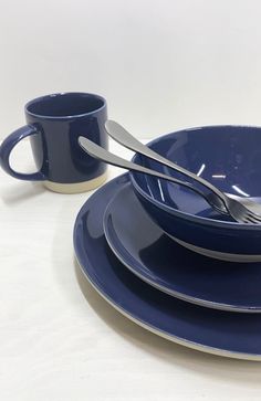 a set of blue dinnerware with two cups and spoons on the plate next to each other