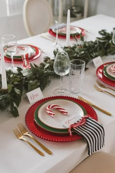 a table set for christmas dinner with candy canes and greenery