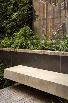 a concrete bench sitting in front of some plants