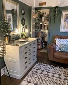 a living room filled with furniture and lots of plants on top of the dressers