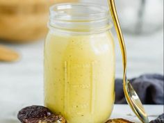 a glass jar filled with fruit next to an open cookie on a plate and two spoons