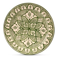 a green and white plate with an intricate design on the front, sitting on a white surface