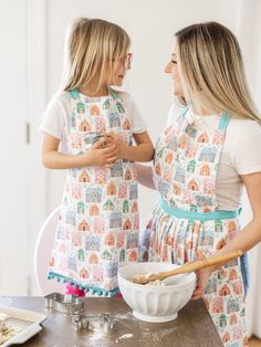 two girls in aprons are cooking together