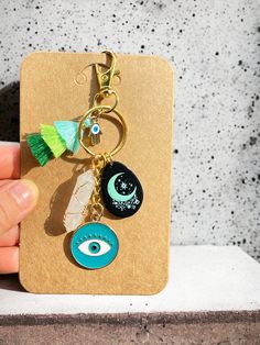 a hand holding a keychain with charms on it and an evil eye charm