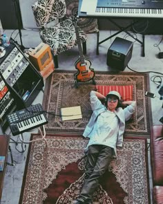 a man laying on top of a rug next to musical equipment