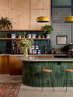 a kitchen with two stools next to a counter top and shelves filled with plants