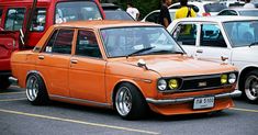 an orange car parked in a parking lot next to other cars