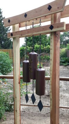 a wooden structure with two bells hanging from it's sides and chains attached to them