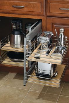 an open drawer in a kitchen with dishes and utensils on the bottom shelf