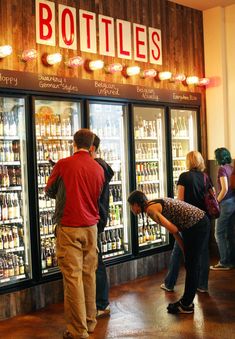 people standing in front of a display case filled with bottles