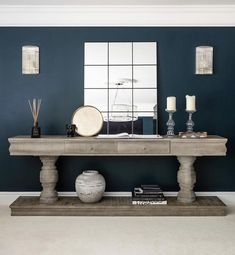 a living room with blue walls and a large console table in the middle, surrounded by candles