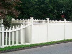 a white picket fence next to a street