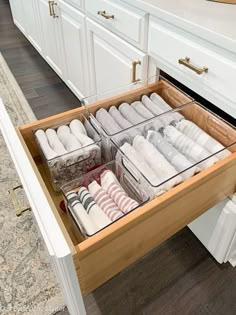 an open drawer in the middle of a kitchen with towels and other items inside it