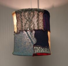 a lamp hanging from a ceiling with different colored sweaters on it's sides