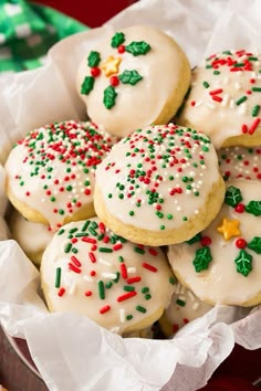 a basket filled with white frosted cookies covered in sprinkles and green leaves