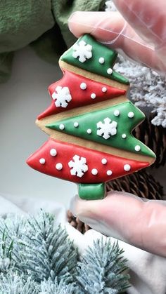 a hand holding a decorated christmas tree cookie