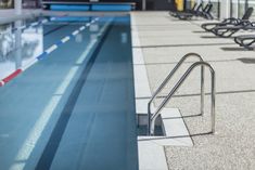 an empty swimming pool with benches and chairs around the edge is seen in this image