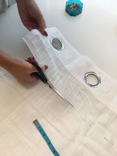 a person cutting fabric with scissors on a table next to tape measure and other items