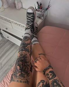 a person with tattoos on their legs and leggings is sitting in a bed