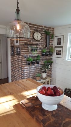 a bowl of fruit sitting on top of a wooden table in front of a brick wall