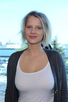 a woman with blonde hair standing in front of a window