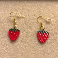 two pairs of earrings with red and green bead designs on them, sitting on a carpet