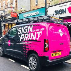 a pink van is parked on the side of the road in front of shops and businesses