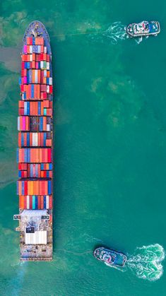 two boats in the water near a large container ship