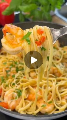 someone is holding a fork full of pasta with shrimp