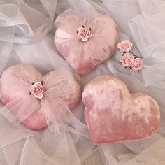 three pink heart shaped cushions with roses on them and tulle netting around the edges