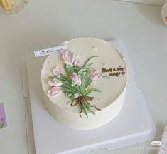 a white cake with flowers on it sitting on top of a table next to other items