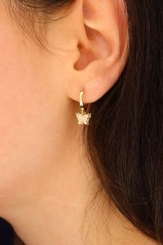 Crafted with elegance and charm, these 14K Gold Butterfly Dangle Hoop Earrings are a delicate and stylish accessory for any occasion. The intricate design features fluttering butterfly charms hanging gracefully from the gold hoops, adding a whimsical touch to your look. Made from high-quality 14K gold, these earrings offer a luxurious shine that catches the light beautifully. Perfect for adding a touch of nature-inspired beauty to your ensemble, these earrings are versatile and eye-catching. Whe Elegant Gold Huggie Earrings With Dangling Charms, Butterfly Charm Huggie Earrings As Gift, Elegant Huggie Earrings With Butterfly Charm, Dainty Hoop Earrings With Butterfly Charm, Gold Dainty Hoop Earrings With Butterfly Charm, Elegant Huggie Jewelry With Butterfly Charm, Fluttering Butterfly, Earrings Hanging, Dangle Hoop Earrings