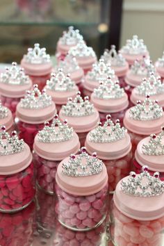 there are many candy jars with tiaras on them and pink candies in the bottom