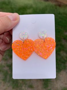 a pair of orange heart shaped earrings with white and pink flecks on them