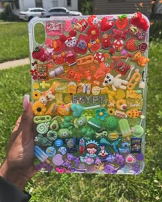 someone is holding up a case with many different buttons on it in the grass near a house