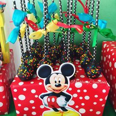 there is a mickey mouse cake on the table with many candy sticks in front of it