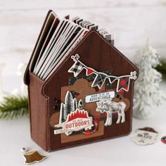 a small wooden house with some stickers on the front and side, sitting next to christmas decorations