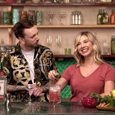 a man and woman sitting at a bar with drinks in front of the bar counter