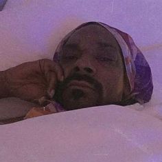 a man laying in bed with his head on the pillow while talking on a cell phone