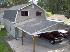 a black truck is parked in front of a gray house with an attached carport