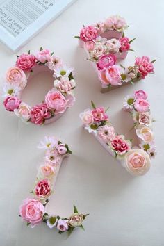 flowers are arranged in the shape of letters on a white table with an open book