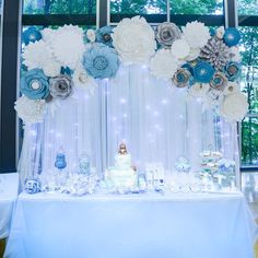 a table topped with a white cake and lots of blue flowers on top of it