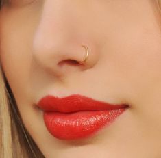 a close up shot of a woman's nose with red lipstick and gold nose ring