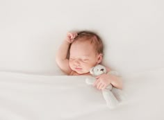 a baby sleeping with a stuffed animal in his arms