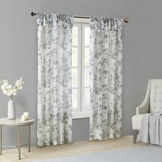 a living room with gray walls and curtains on the window sill, white chair and table