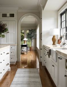 a kitchen with white cabinets and wood floors