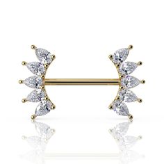 a pair of gold piercings with white stones on top and two smaller diamonds in the middle