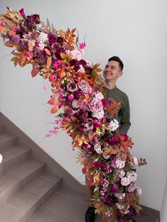 a man standing next to a bunch of flowers on top of a set of stairs