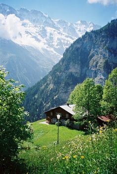 a house in the mountains with snow on the top of it's mountain tops